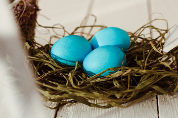 Multicolored Easter eggs in wicker basket on white wooden background