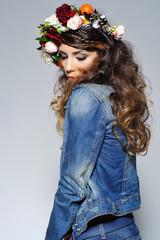 Fashion portrait of a beautiful young woman with gipsy hairstyle wearing handmade statement flower crown and trendy jeans outfit