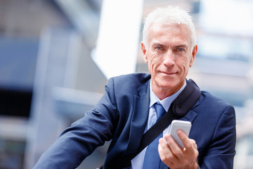 Successful businessman on bicycle with mobile phone