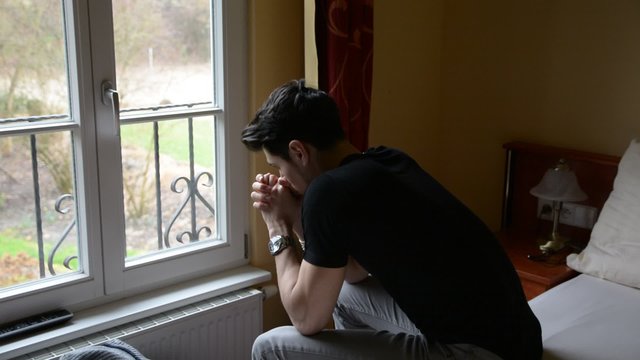 Young Man Sitting On Bed Sad Or Worried, Thinking