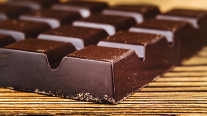 Black chocolate bar on wooden table, close-up