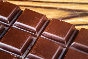 Black chocolate bar on wooden table, close-up