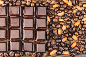 Dark chocolate cubes, coffee beans, peanuts and raisins, top view