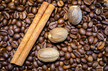 Brown coffee beans, .nutmeg and cinnamon sticks background