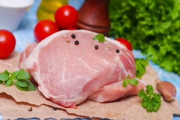 Sliced pieces of raw meat for barbecue with fresh Vegetables (tomatoes, lettuce) on wooden surface. Meat raw stacked on wooden background, beef Steak BBQ. 