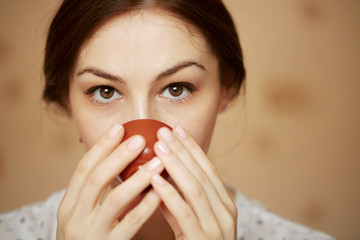 Close up of a cute brunette woman drinking tea at home