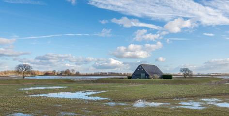 Old black painted wooden barn surrounded by a dike © Ruud Morijn