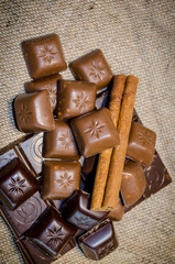 chocolate bar and cinnamon sticks on a sack background