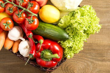 Wicker basket with fruits and vegetables on wooden table