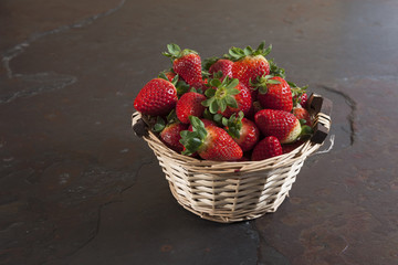 Fresh strawberries basket on dark stone table