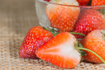 Ripe strawberries in saucer on wooden table on blurred backgroun