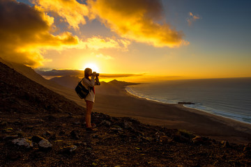 Beautiful seascape view on Cofete coastline with young female traveler on the sunset on Fuerteventura island in Spain. General plan with a lot of space - Powered by Adobe