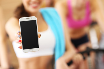 Fit woman holding smartphone in gym