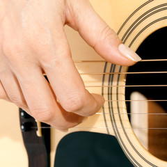 woman's hand on the guitar strings closeup