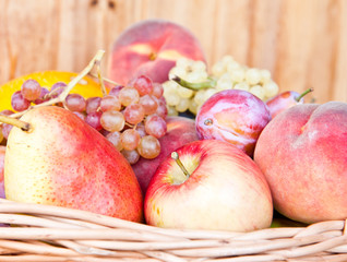 Fresh fruits in a basket against wooden wall