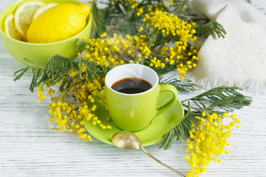 mimosa, lemon and coffee on light wooden background