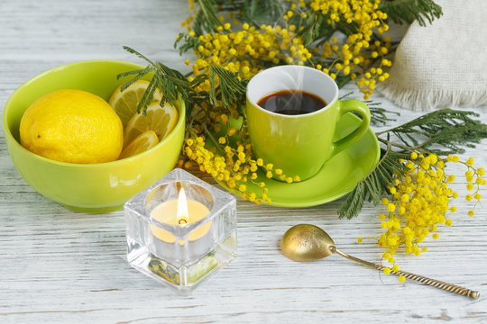 mimosa, lemon and coffee on light wooden background