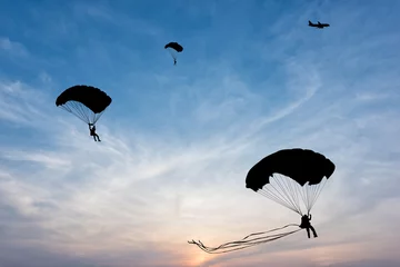 Foto auf Acrylglas Luftsport Schattenbild des Fallschirms und des Flugzeugs auf Sonnenunterganghintergrund
