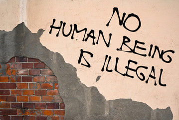 Handwritten graffiti No Human Being Is Illegal sprayed on the wall, anarchist aesthetics 