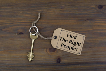 Key and a note on a wooden table with text. Find the Right Peopl