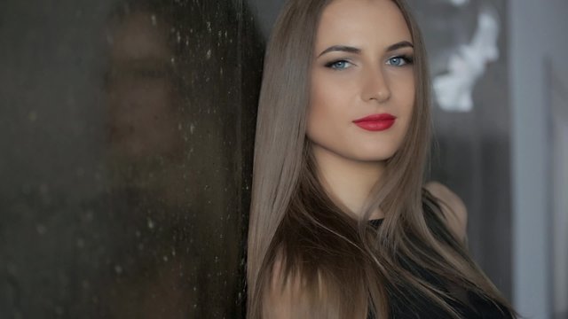 Brunette with red lips posing at the wall