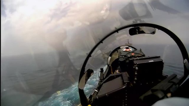 POV shot of a fighter jet landing on an aircraft carrier.