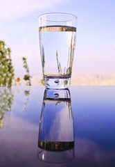 glass with water reflection on table - evening sunset background