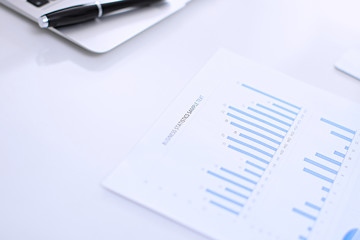 Office workplace with a laptop and financial documents on the light reflecting table