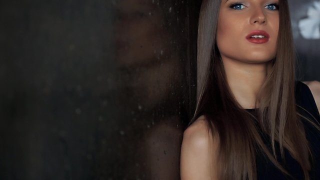 Brunette with red lips posing at the wall