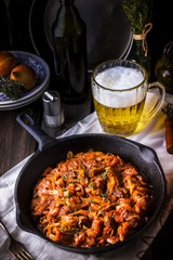 Stewed cabbage  in a vintage frying pan and a mug with beer.