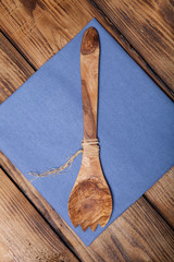 Blue kitchen towel and wooden spoon on old wooden burned table o