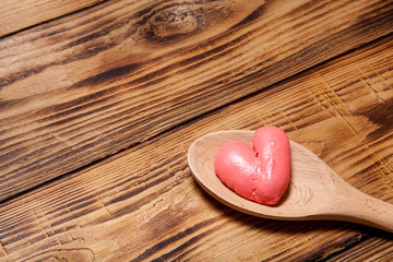 Wooden spoon and red hearts on old wooden burned table or board