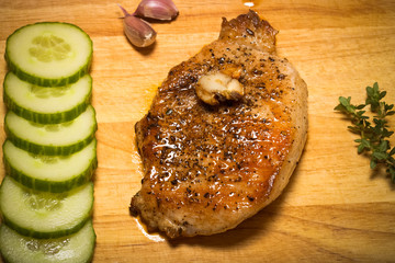 Fresh fried meat with thyme, garlic and cucumber on light wooden