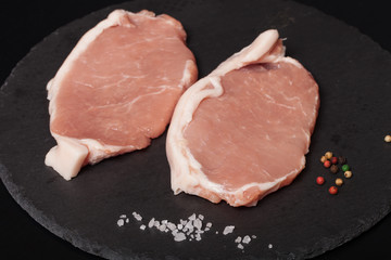 Fresh meat steaks on black slate background. Selective focus