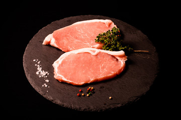 Fresh meat steaks on black slate background. Toned