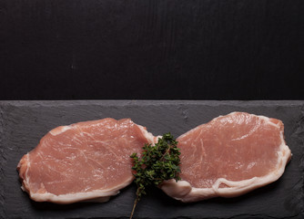 Fresh meat steaks on black slate background