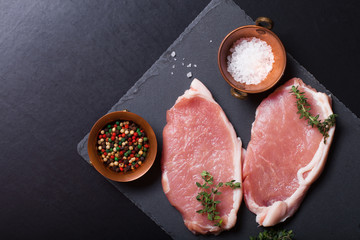 Fresh meat steaks on black slate background