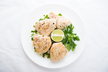 Chicken breasts with parsley and citrus on white background top view. Healthy food.