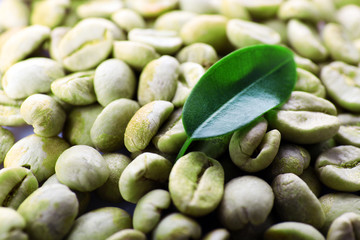 Heap of green coffee beans with leaf close up