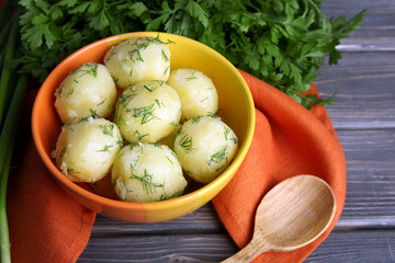 Boiled potatoes with greens in bowl on table close up
