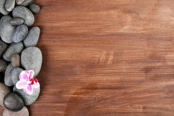 Spa stones and orchid on wooden background