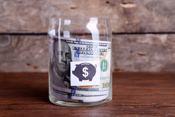 Roll of dollar banknotes for different needs in a glass jar on a table