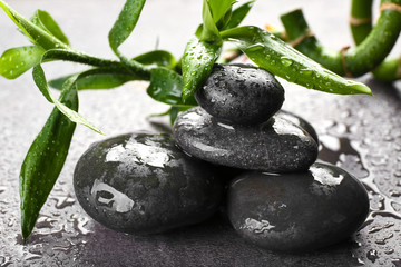 Fototapeta na wymiar Hot spa stones with bamboo on grey background, close-up