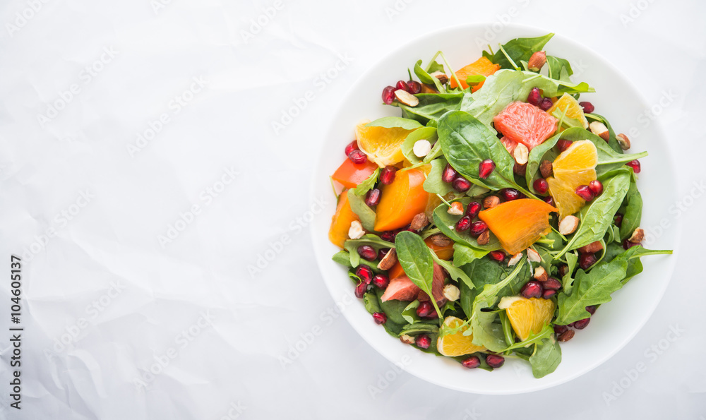 Wall mural fresh salad with fruits and greens on white background top view with space for text. healthy food.