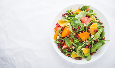 Fresh salad with fruits and greens on white background top view with space for text. Healthy food.