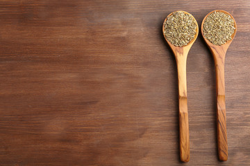 Two wooden spoons with cumin on the table, close-up