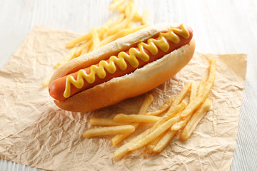 Hot dog and fried potatoes on wooden background
