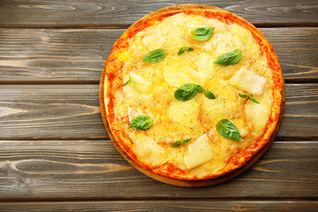 Tasty pizza decorated with basil  on wooden background, close up