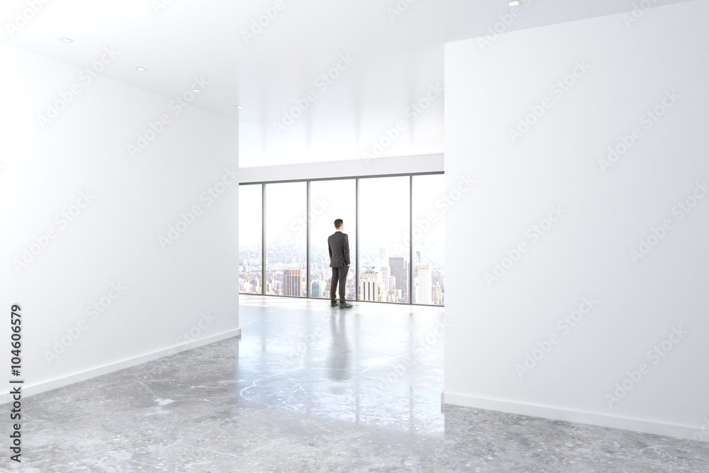 Poster businessman looking out the window in empty office with concrete