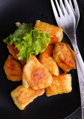 chicken nuggets in a black plate on a black background